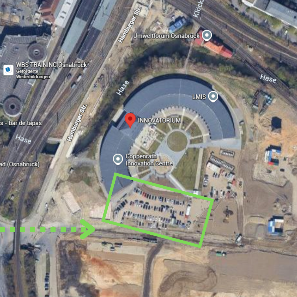 Luftbild des INNOVATORIUM Osnabrück mit grün markiertem Parkplatz südlich des Gebäudes und Pfeil, der die Zufahrt über die Baustelle zeigt